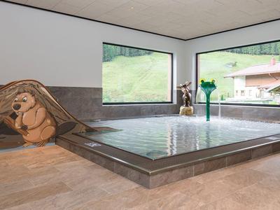 Indoor area with modern rectangular pool and large windows overlooking green hills.
