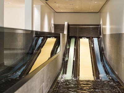 Interior view of a modern hotel pool with water slides and reflective walls.