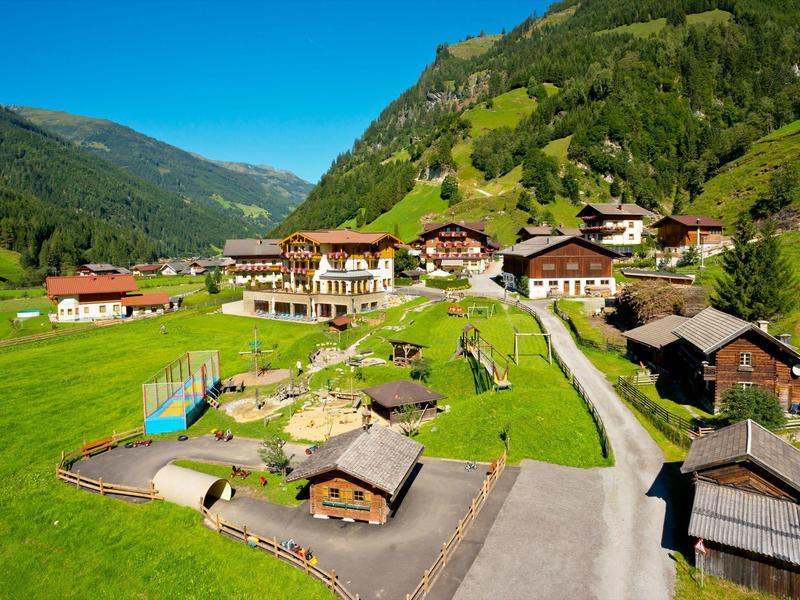 Bergdorf mit traditionellen Chalets und grünen Wiesen unter klarem blauem Himmel