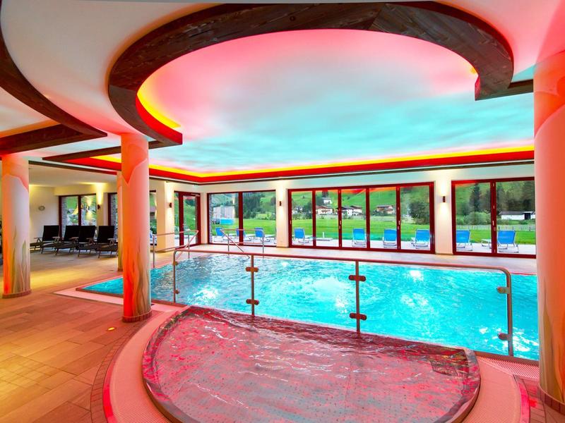 Modernes Hallenbad mit beleuchtetem Whirlpool und Panoramafenstern zum Garten.