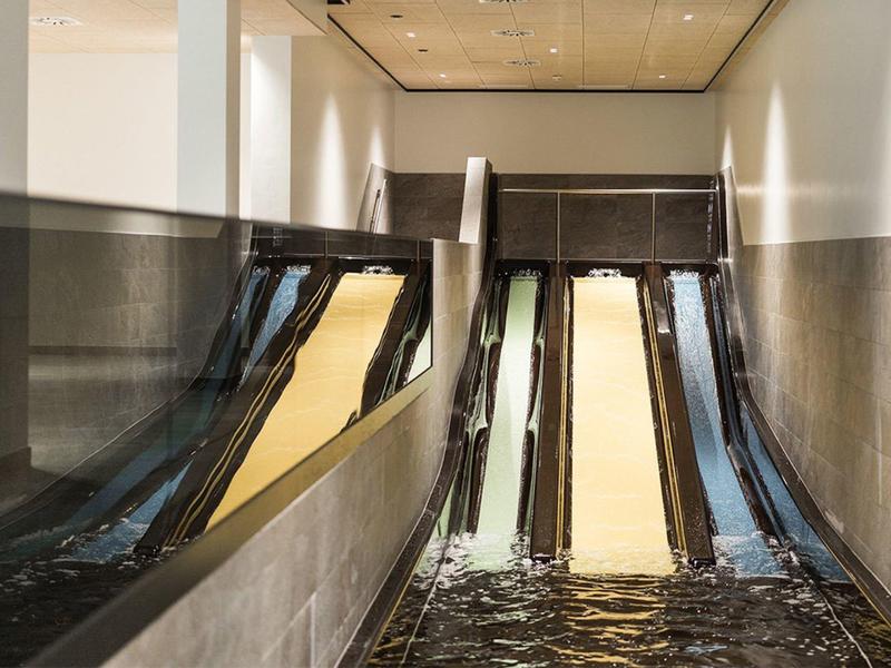 Innenansicht eines modernen Innenpools mit Wasserfall und weißen Wänden