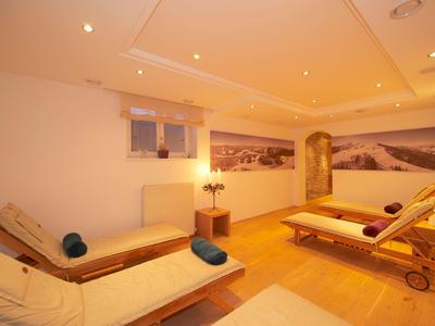 Helles Wellnesszimmer mit zwei Liegen, warmem Holzfußboden und beruhigender Wandkunst.