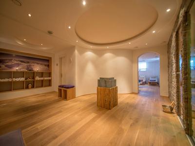 Moderner Raum mit hellem Holzboden, rundem Deckenelement, Skulptur und offener Tür zum Wohnzimmer.