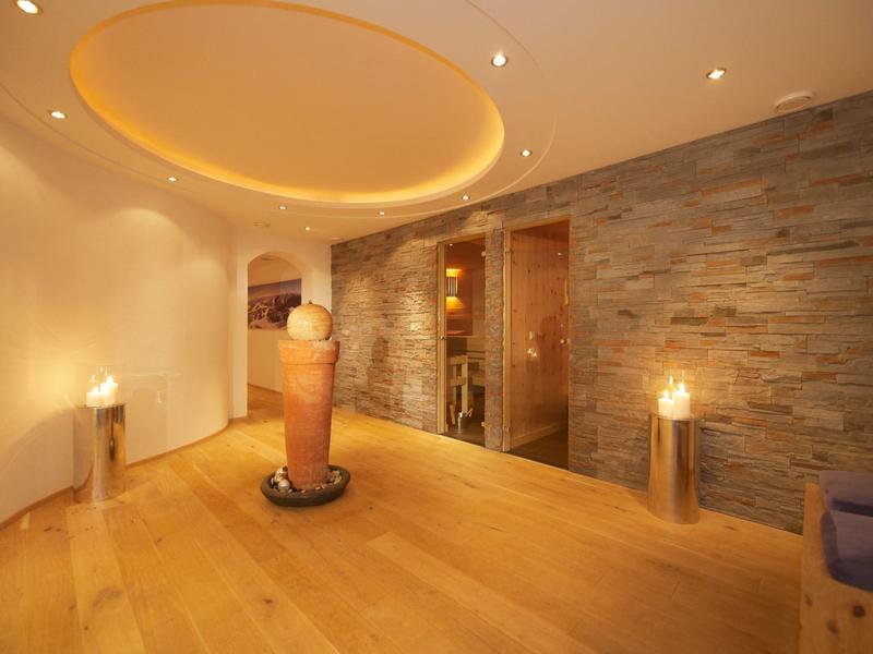Moderner Wellnessraum mit warmem Licht, Holzfußboden, Steinwand und dekorativem Brunnen.