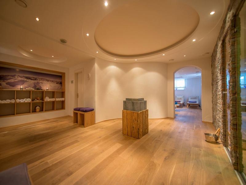 Moderner Raum mit hellem Holzboden, rundem Deckenelement, Skulptur und offener Tür zum Wohnzimmer.