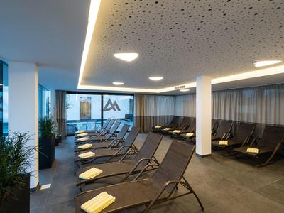 Salle de détente moderne avec chaises longues, lumière douce et grandes fenêtres.