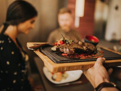 Serveur apporte une assiette de viande grillée dans un restaurant.