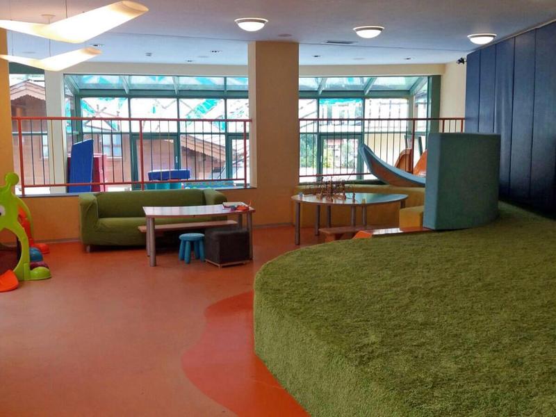 Espace de jeux pour enfants avec tapis vert, mur d'escalade et sièges colorés