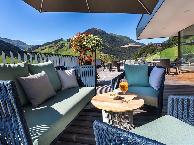 Terrasse confortable avec sièges agréables et vue sur la montagne par une journée ensoleillée.