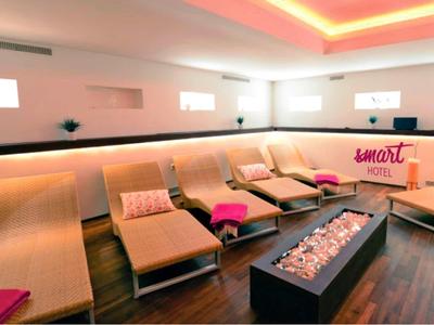 Modern gestalteter Ruheraum mit Liegen, indirekter Beleuchtung und einem langen Kaminfeuer.