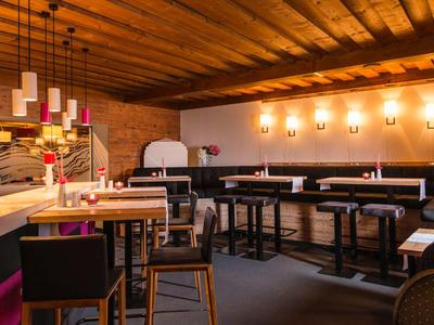 Ristorante moderno con soffitto in legno, mobili scuri e illuminazione d'atmosfera.