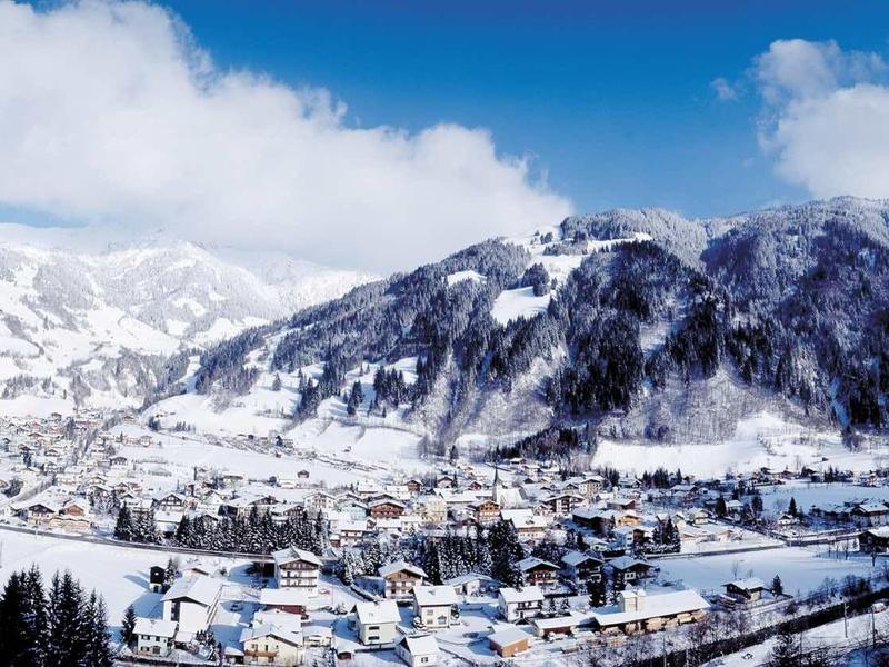 Winterliche Alpenlandschaft mit schneebedeckten Bergen, blauen Himmel und Dorf im Tal.