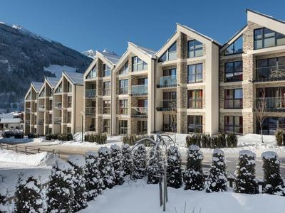 Modern hotelcomplex met balkons, omgeven door besneeuwd landschap en bergen op de achtergrond.