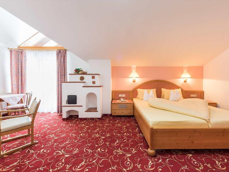 Chambre d'hôtel lumineuse avec lit double, tables de chevet et moquette rouge.
