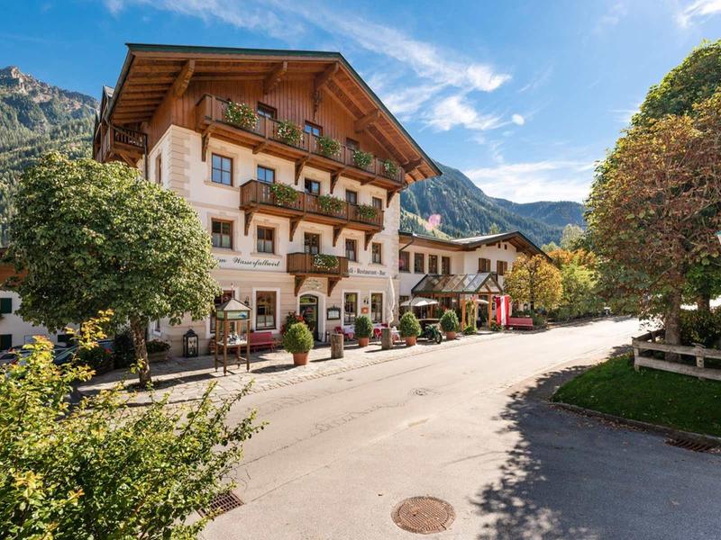 Bâtiment hôtelier au style alpin rustique dans un paysage montagneux pittoresque par temps ensoleillé.
