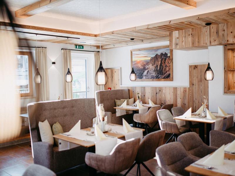 Jasna restauracja z drewnianym stropem, nowoczesnymi krzesłami i dekoracyjnymi lampami.