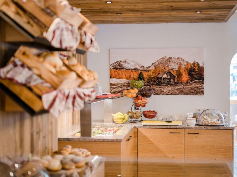 Przytulny kącik śniadaniowy z świeżymi bułkami, owocami i bufetem w hotelu.