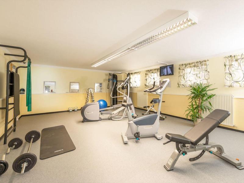 Jasna siłownia z różnymi urządzeniami do ćwiczeń i dużymi oknami.