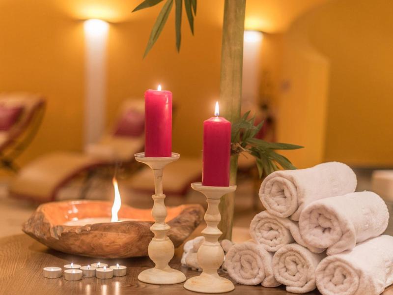 Różowe świece i zwinięte ręczniki w relaksującym spa z miękkim oświetleniem.