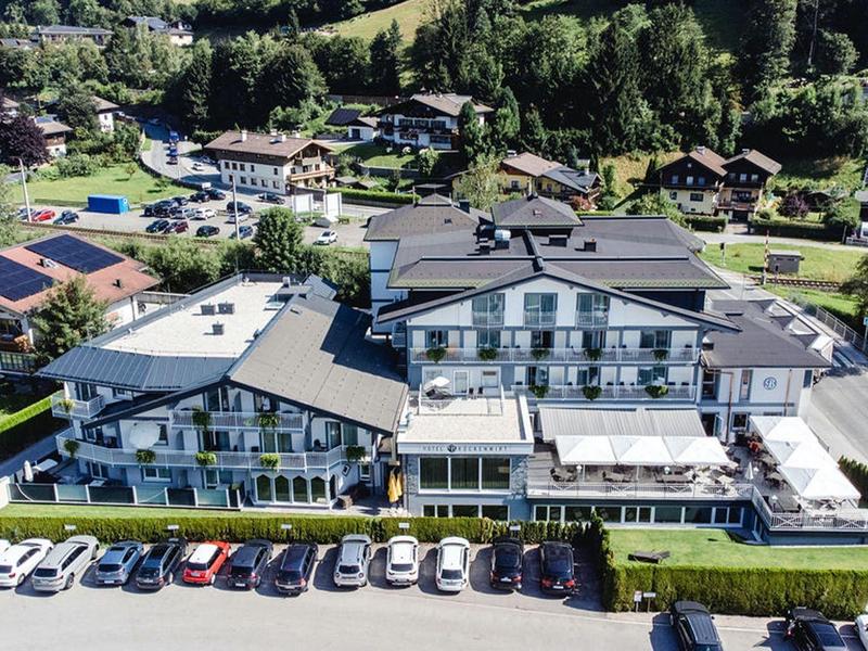 Duży hotel z miejscami parkingowymi na zielonym górskim terenie.