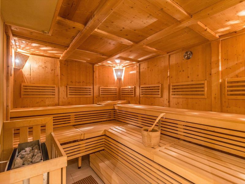 Przytulna sauna z drewnianymi ławkami i ciepłym światłem do relaksu.