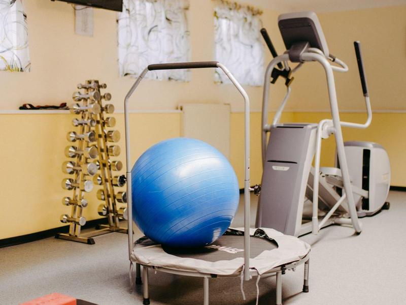 Mała siłownia z trampoliną, piłką do ćwiczeń i hantlami w przytulnym pomieszczeniu.