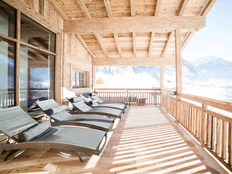 Velký balkon s lehátky a výhledem na hory v chatě.