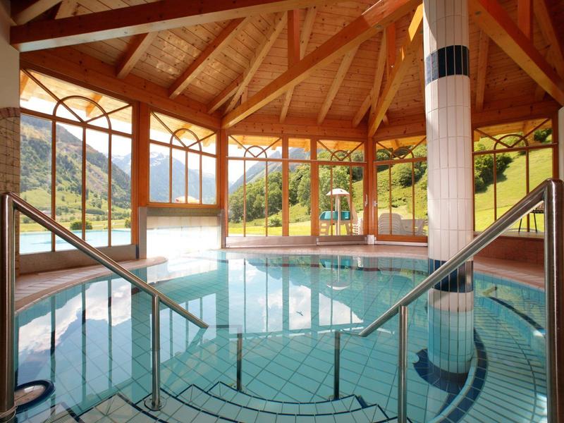 Vnitřní bazén s velkými dřevěnými okny s výhledem na venkov.