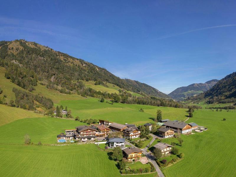 Horská vesnice s zelenými loukami a modrou oblohou v údolí