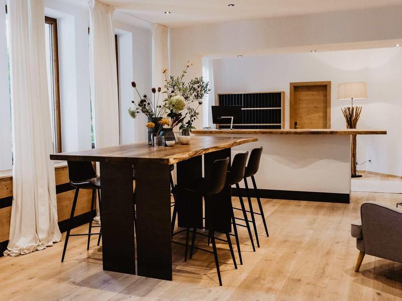 Nowoczesna jadalnia z wysokim stołem, krzesłami i aneksem kuchennym w jasnym pokoju