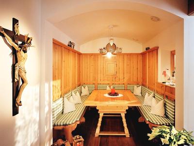 Coin en bois confortable avec table et bancs, décoré de bougies et d'une croix au mur.