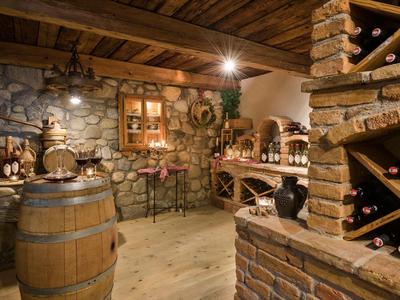 Cave à vin rustique avec poutres en bois, murs en pierre, étagères et baril à vin.