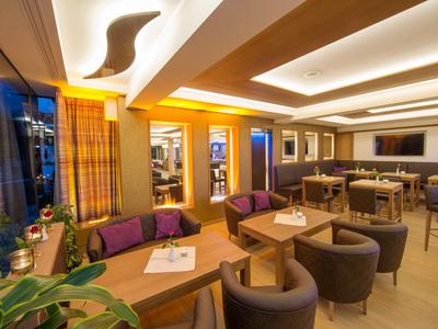 Intérieur lumineux et moderne d'un bar d'hôtel avec des fauteuils confortables et un éclairage chaleureux.