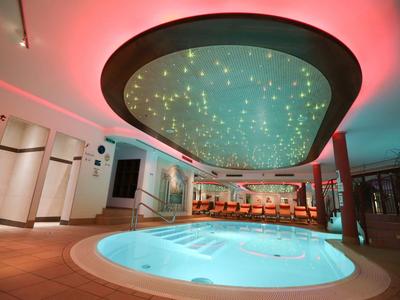 Espace bien-être moderne avec jacuzzi éclairé et plafond étoilé.