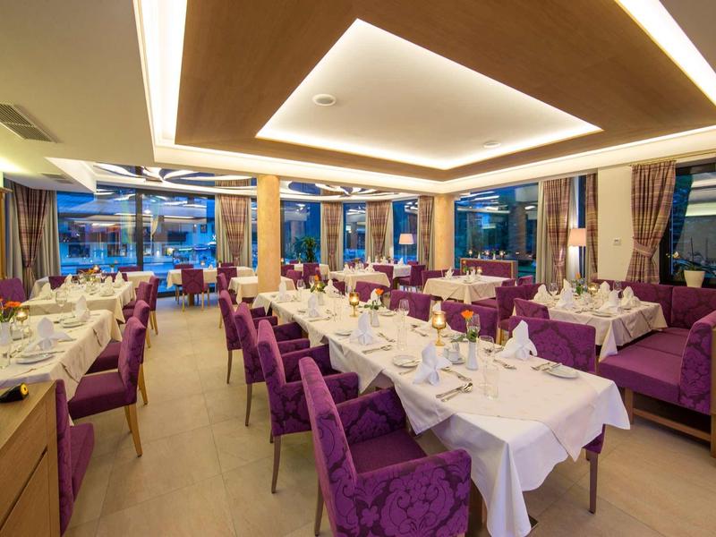 Restaurant d'hôtel élégant avec chaises violettes et tables blanches dressées.