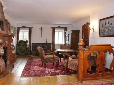 Accogliente salotto con mobili antichi, tappeti rossi e luce calda in un edificio storico.