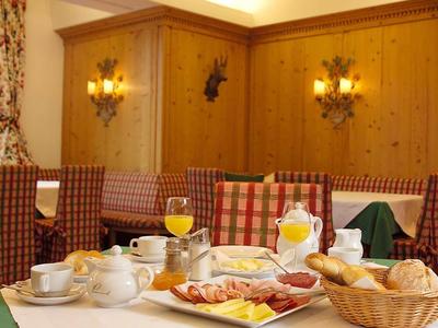 Příjemný jídelní kout s prostřeným stolem, dřevěnými židlemi a obloženými stěnami.