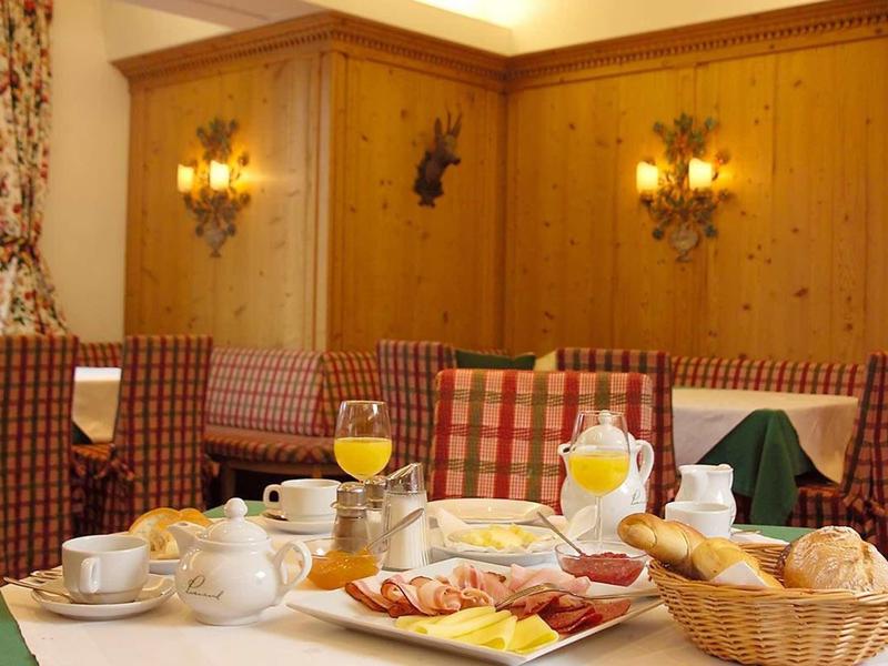 Příjemný jídelní kout s prostřeným stolem, dřevěnými židlemi a obloženými stěnami.