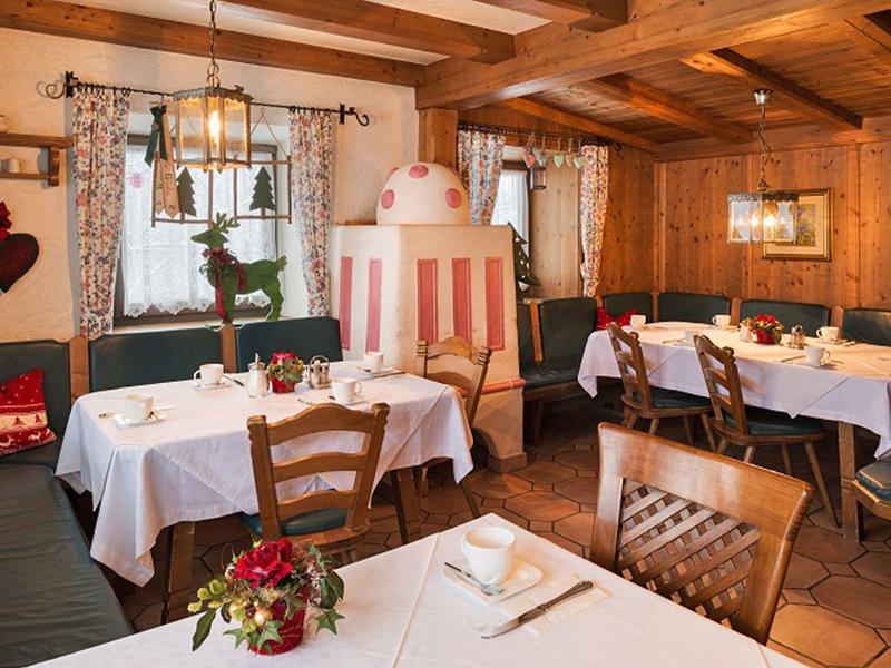 Gezellige rustieke eetkamer met houten balken, witte tafelkleden en bloemrijke decoratie op tafels.