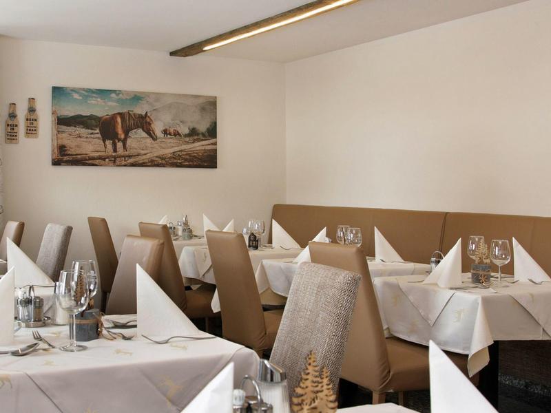 Gezellige restaurantinterieur met tafels gedekt met witte servetten en glaswerk.