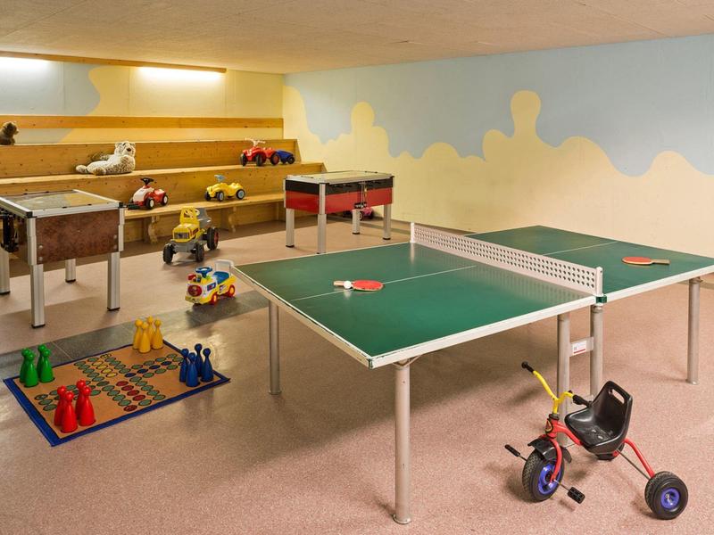 Indoor speelkamer met tafeltennis, tafelvoetbal, speelgoed en driewielers voor hotelgasten.