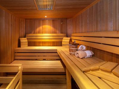 Sauna en bois avec bancs à plusieurs niveaux et serviettes sur le banc.