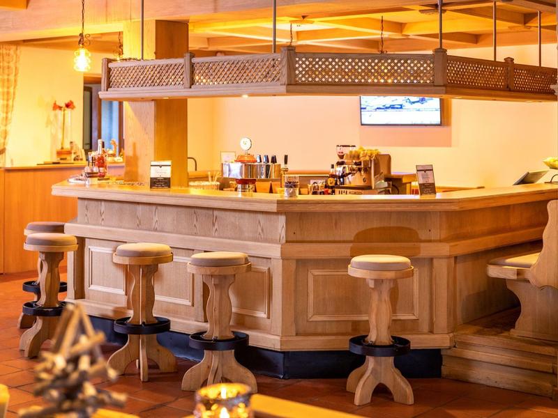 Bar d'hôtel confortable avec comptoir en bois et tabourets hauts, éclairage chaud en arrière-plan.