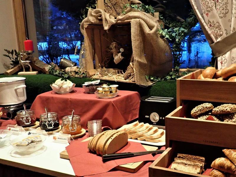 Buffet de petit-déjeuner confortable avec pain, petits pains, croissants et confiture près des fenêtres.