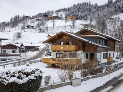 Holzhaus auf schneebedecktem Hang mit Bergen im Winter