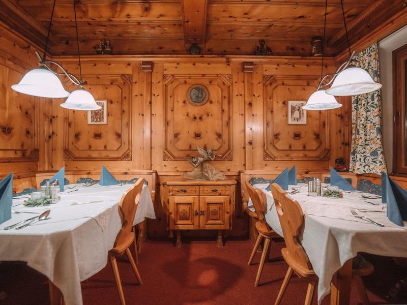 Gemütlicher Holzraum mit zwei gedeckten Tischen und warmem Deckenlicht.