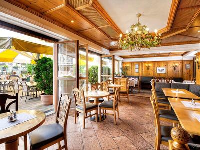 Gemütliches Restaurant mit Holzdecke, runden Tischen, Stühlen und Blick auf Terrasse.