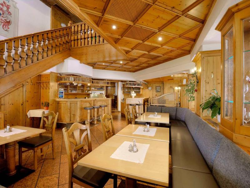 Cozy restaurant area with wood paneling and set tables under warm lighting.