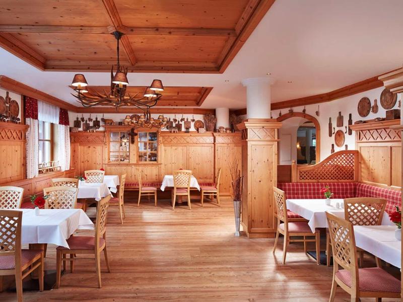 Sala da pranzo arredata in stile rustico con mobili in legno e tavoli apparecchiati in hotel.