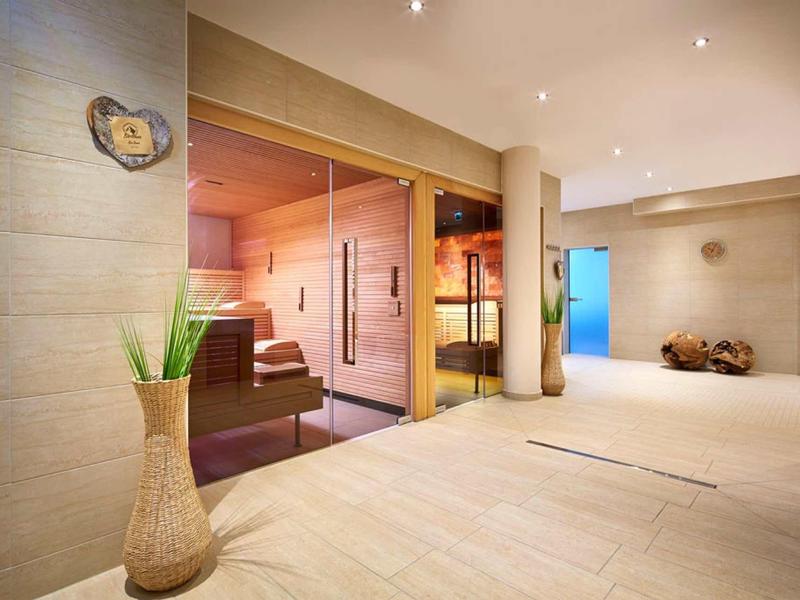 Area benessere moderna con sauna, legno chiaro e atmosfera rilassante.